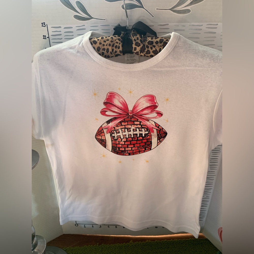 Women’s White Graphic Tee with Pink Bow Football Design